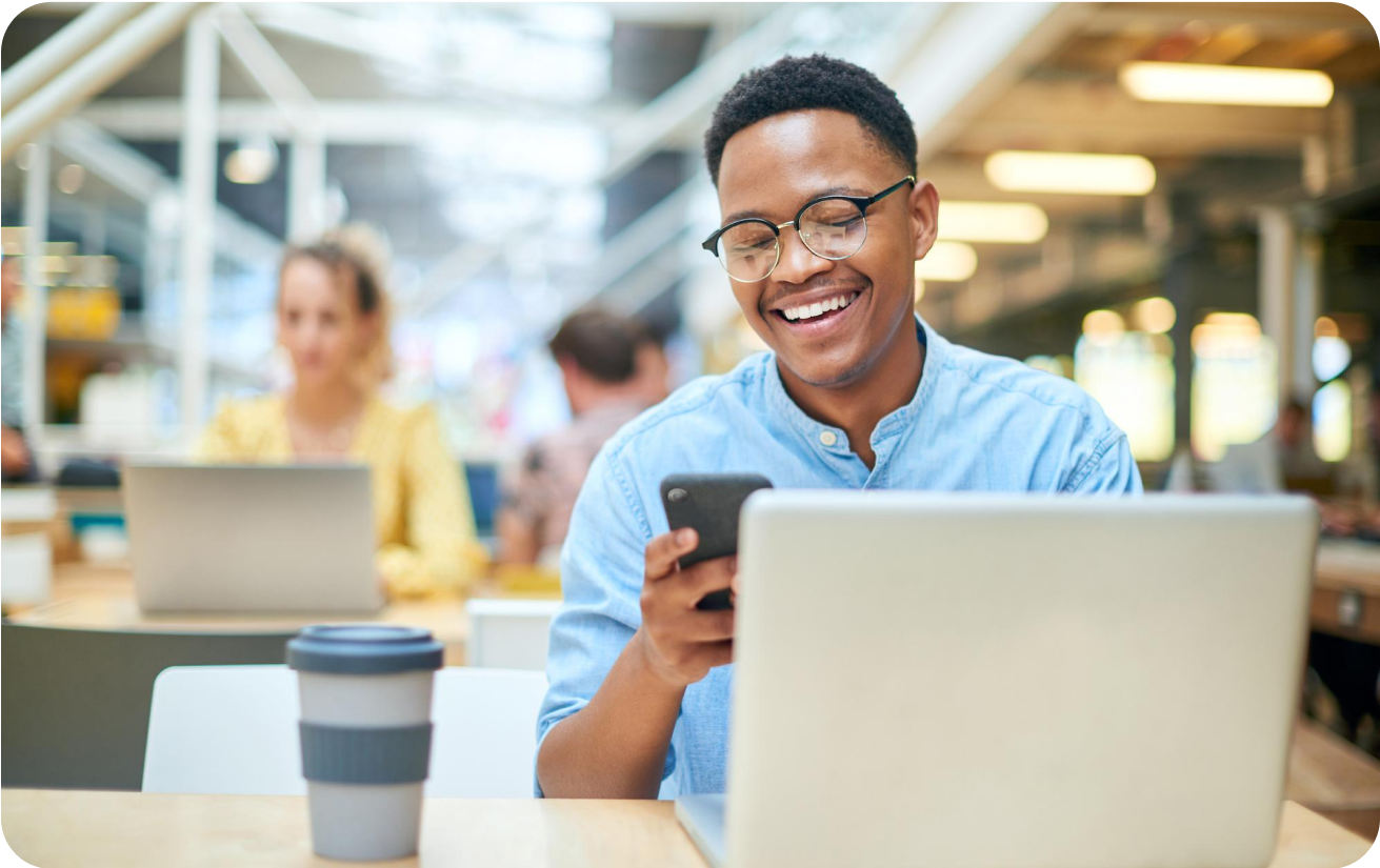 Man looking at mobile phone while on laptop